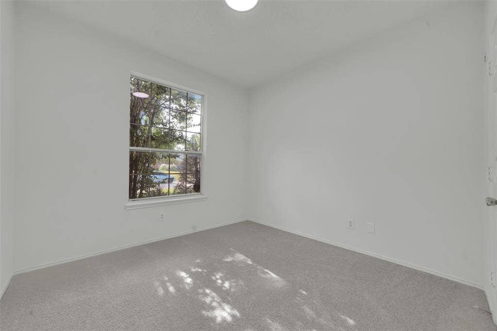 Neutral interior featuring wall-to-wall carpeting, a single-hung window, and a ceiling-mounted light fixture