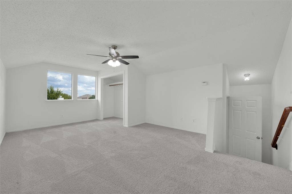 Vaulted ceilings, carpeted flooring, ceiling fan with light fixture, and natural light from dual windows