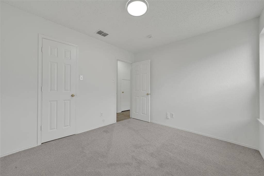 Neutral interior room featuring neutral-tone carpeting, white walls, flush-mount ceiling lighting, and multi-panel interior doors