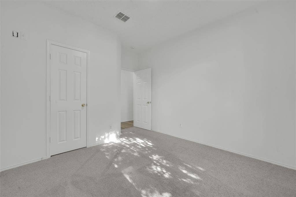 Neutral-toned interior space featuring wall-to-wall carpeting, white walls, and two six-panel interior doors
