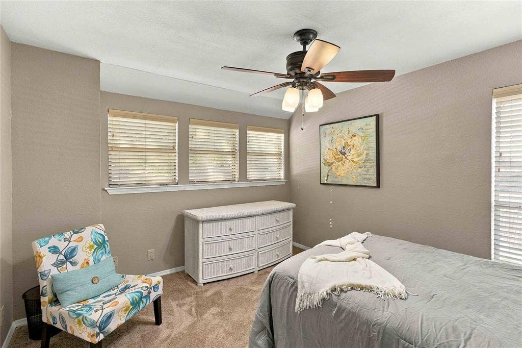 18240 Midway Road, #1706, Dallas, TX 75287 Neutral-toned interior featuring triple-window configuration, carpeted flooring, and a ceiling fan with integrated light fixture