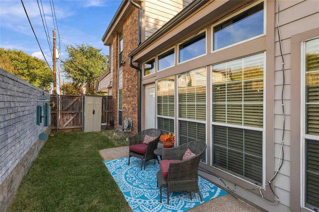 18240 Midway Road, #1706, Dallas, TX 75287 Exterior features include a concrete patio, brick and horizontal siding facade, expansive multi-pane windows, and a privacy wall