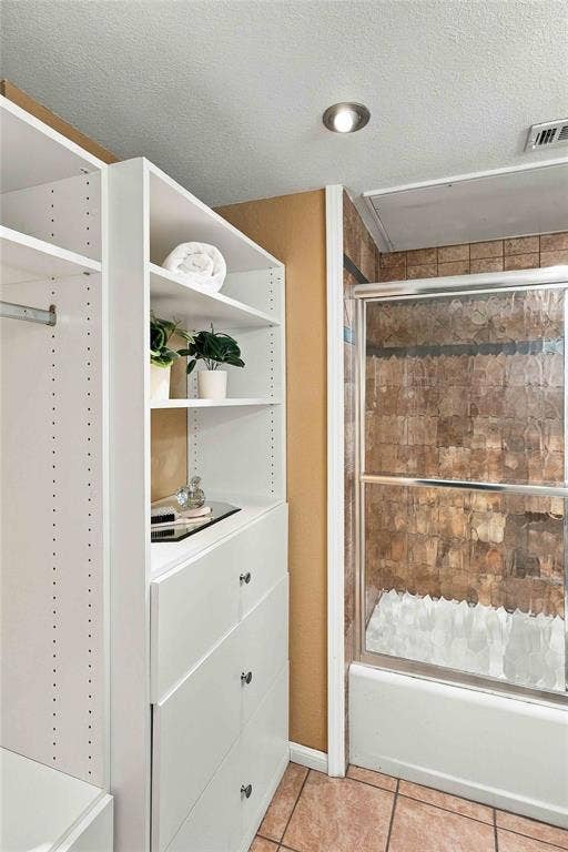 18240 Midway Road, #1706, Dallas, TX 75287 Built-in white storage cabinetry featuring open shelving and drawers, shower enclosure with tiled surround, and ceramic tile flooring