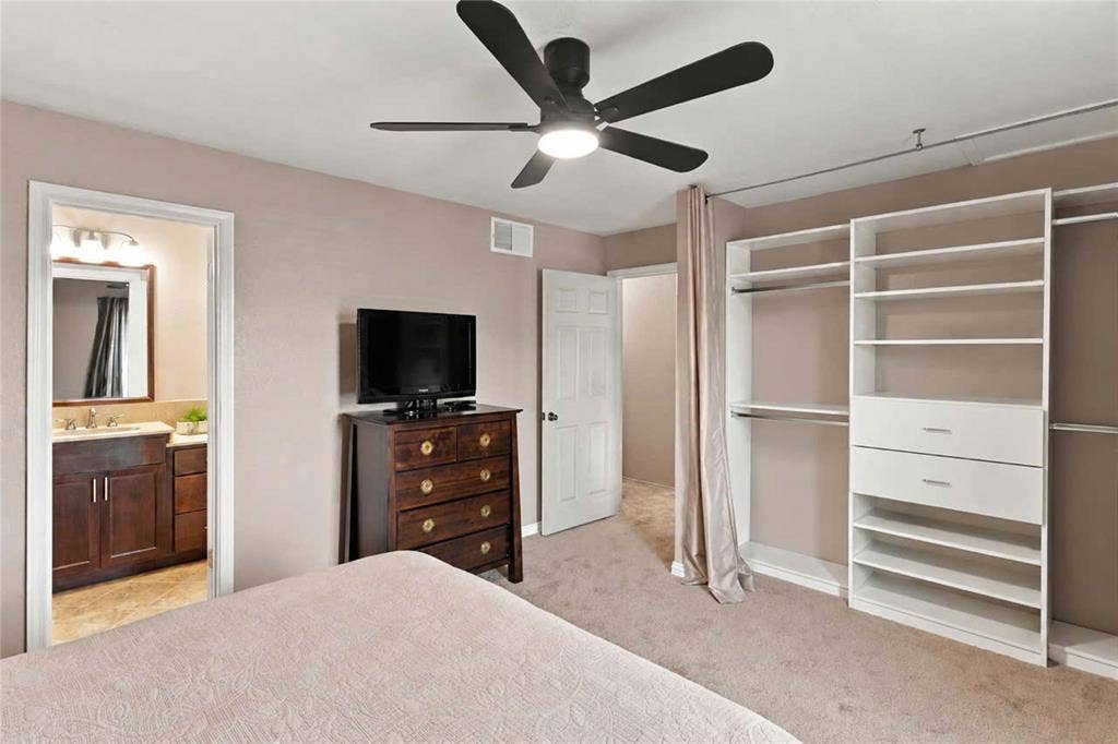 18240 Midway Road, #1706, Dallas, TX 75287 Room featuring a matte black ceiling fan with integrated lighting, wall-to-wall carpeting, and a built-in closet organization system with shelving and drawers