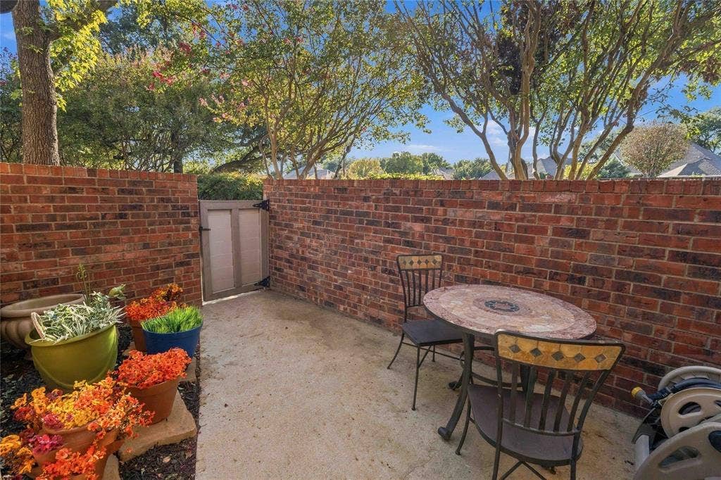 18240 Midway Road, #1706, Dallas, TX 75287 Enclosed outdoor patio featuring a concrete floor, red brick perimeter walls, and a hinged privacy gate