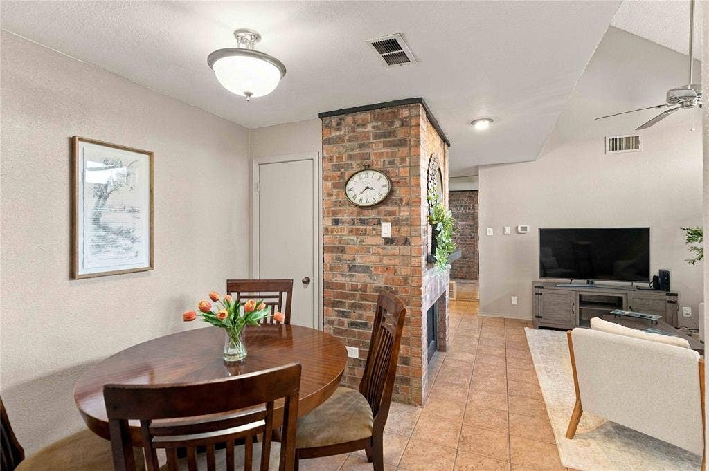 18240 Midway Road, #1706, Dallas, TX 75287 Exposed brick dual-sided fireplace, vaulted ceiling with integrated ceiling fan, and ceramic tile flooring