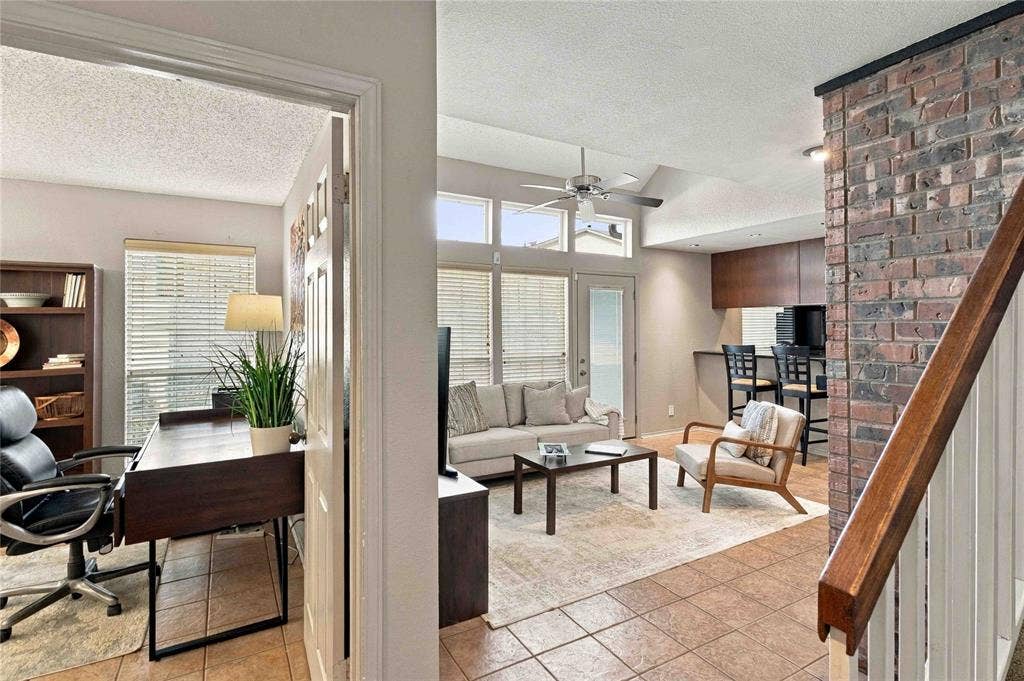 18240 Midway Road, #1706, Dallas, TX 75287 Interior featuring vaulted ceilings, a brick-faced accent wall, tile flooring, and multi-pane windows