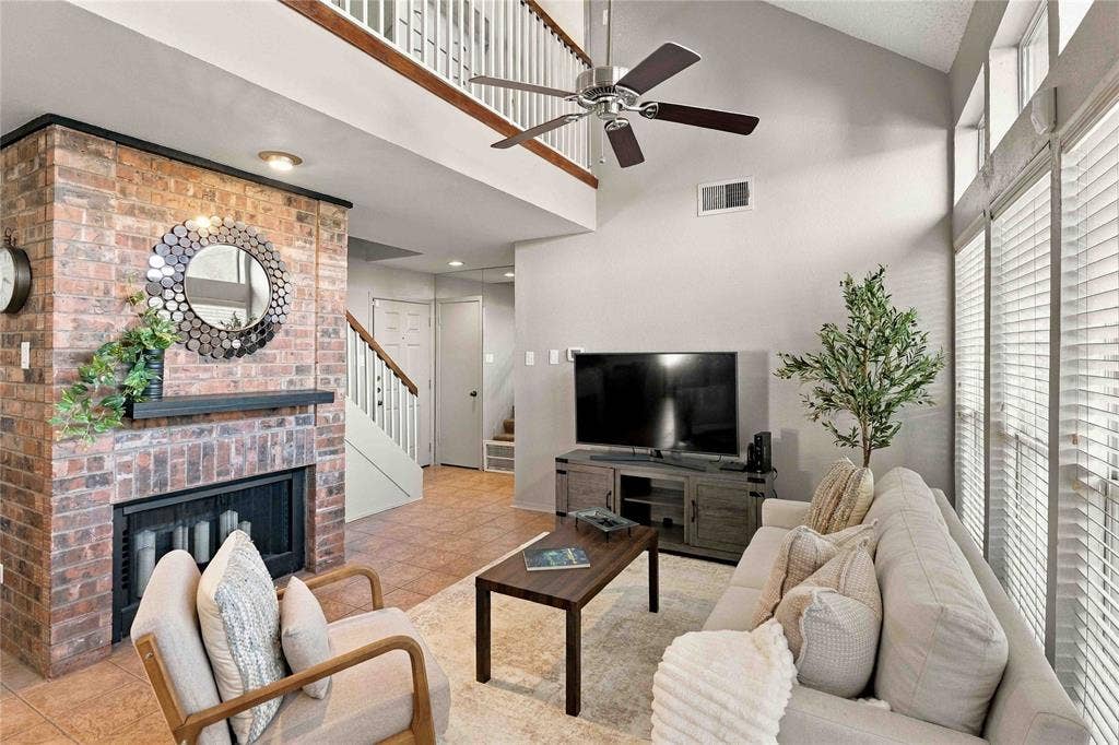 18240 Midway Road, #1706, Dallas, TX 75287 Vaulted ceiling, brick fireplace with a mantel, ceiling fan, and large windows with horizontal blinds