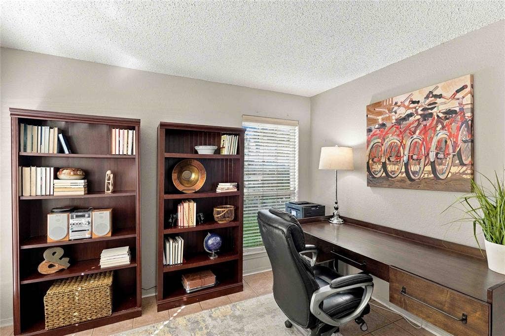 18240 Midway Road, #1706, Dallas, TX 75287 Built-in wall-to-wall wood-finish desk featuring a drawer with dark hardware, paired with two matching tall wood-finish shelving units and horizontal window blinds