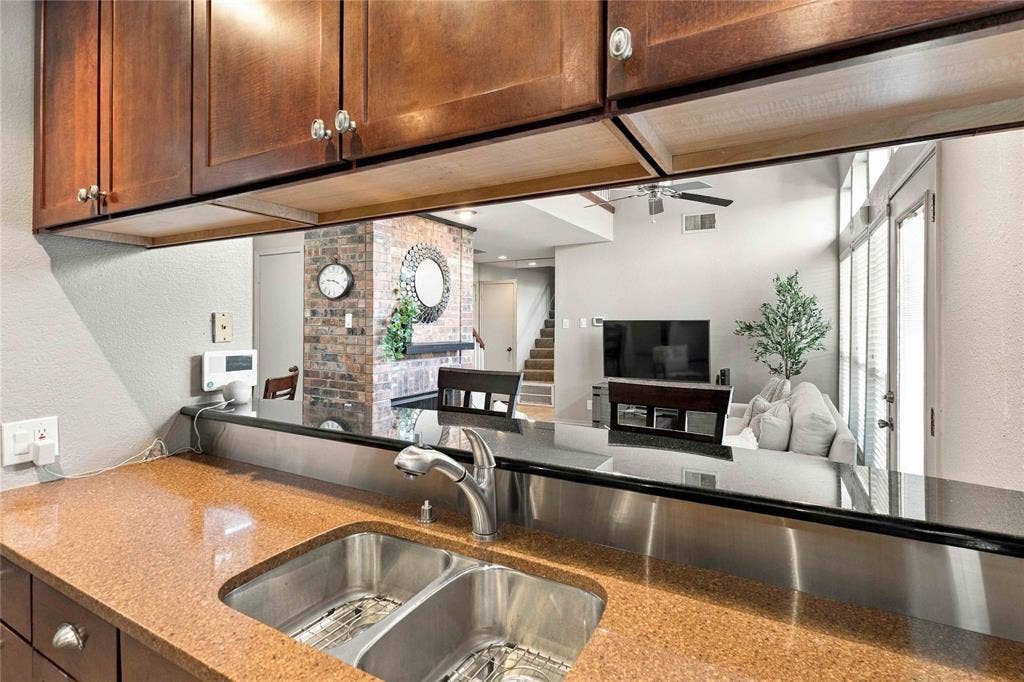 18240 Midway Road, #1706, Dallas, TX 75287 Kitchen featuring dark wood-finish cabinetry, stone countertop, dual-basin stainless steel sink with pull-down faucet, and stainless steel backsplash