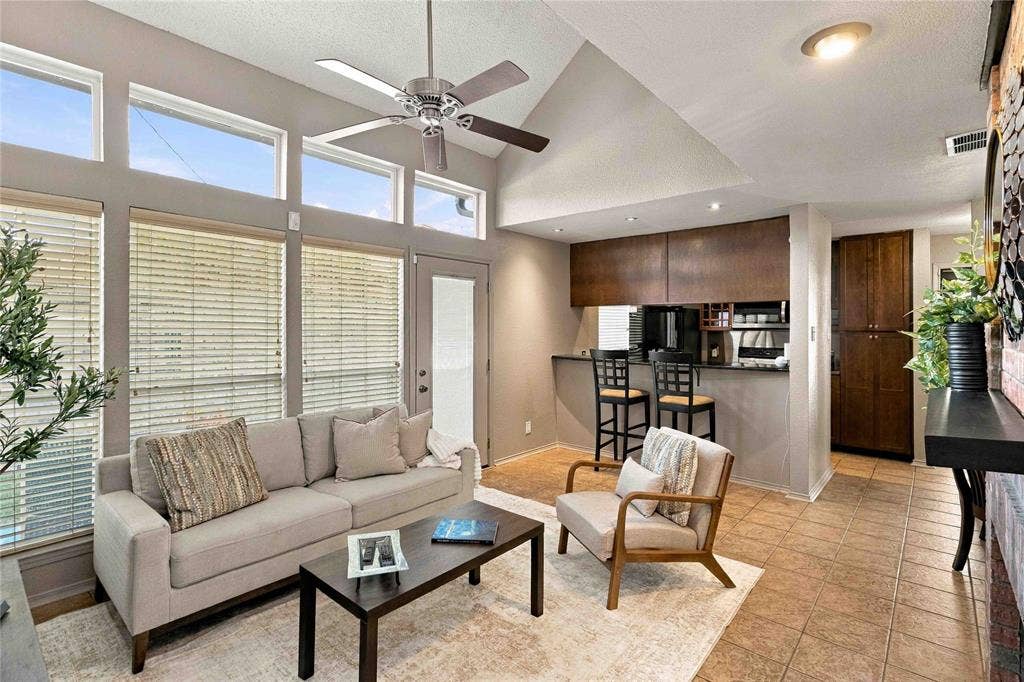 18240 Midway Road, #1706, Dallas, TX 75287 Vaulted ceilings with a ceiling fan, expansive transom windows, ceramic tile flooring, built-in floor-to-ceiling cabinetry, and a kitchen pass-through counter