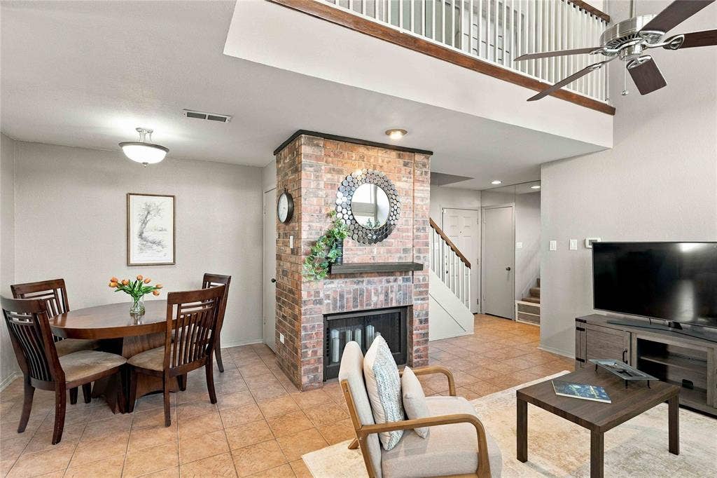 18240 Midway Road, #1706, Dallas, TX 75287 Double-height ceiling, brick-surround fireplace, tile flooring, and metal railing mezzanine