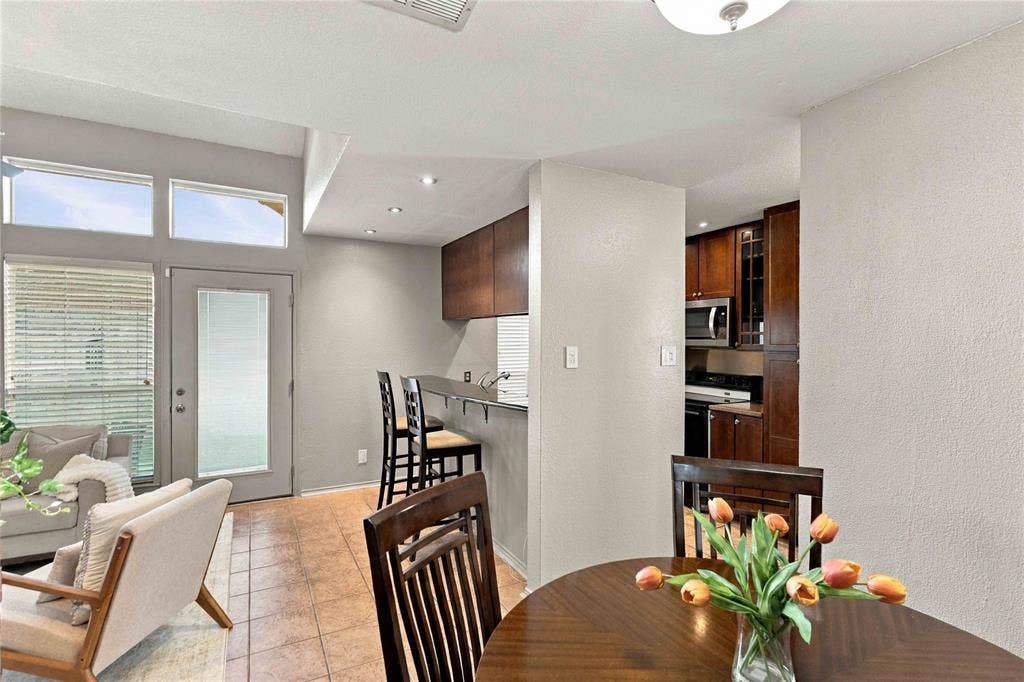 18240 Midway Road, #1706, Dallas, TX 75287 Kitchen featuring a built-in breakfast bar, dark-finish cabinetry, built-in microwave, tile flooring, and high-reaching ceilings with transom windows
