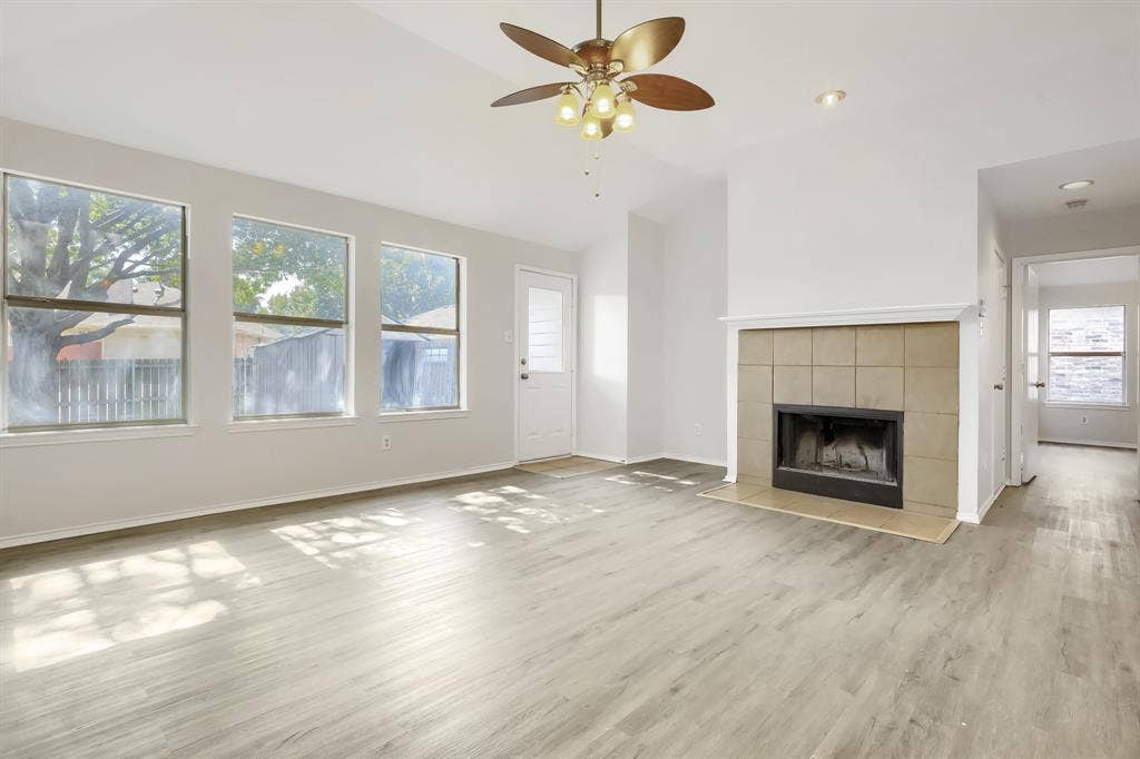 Vaulted ceilings, wood-finish flooring, tile-surround fireplace, and ceiling fan with integrated lighting