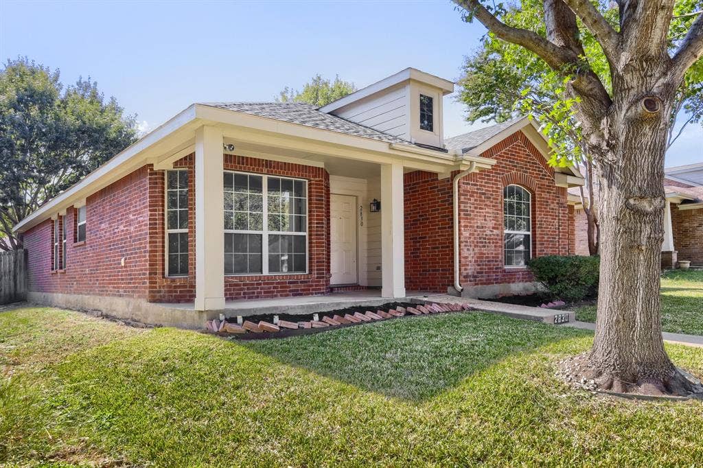 Single-story brick exterior featuring a covered front porch, arched window detailing, and multi-light windows