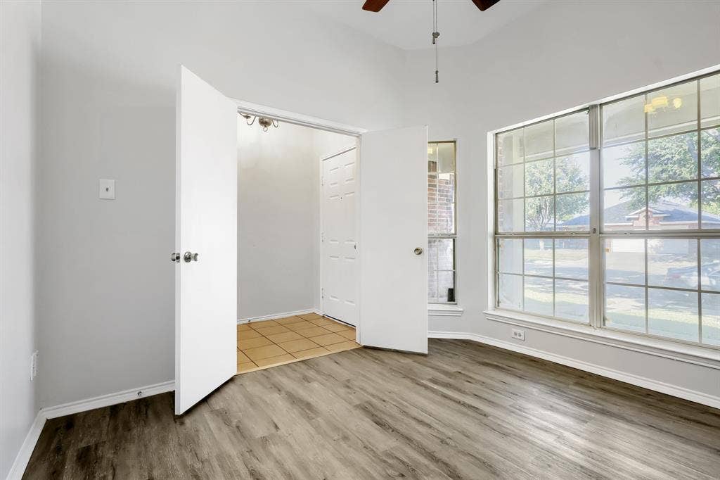 Vaulted ceiling, arched window with a grid pattern, and ceiling fan with integrated light fixture