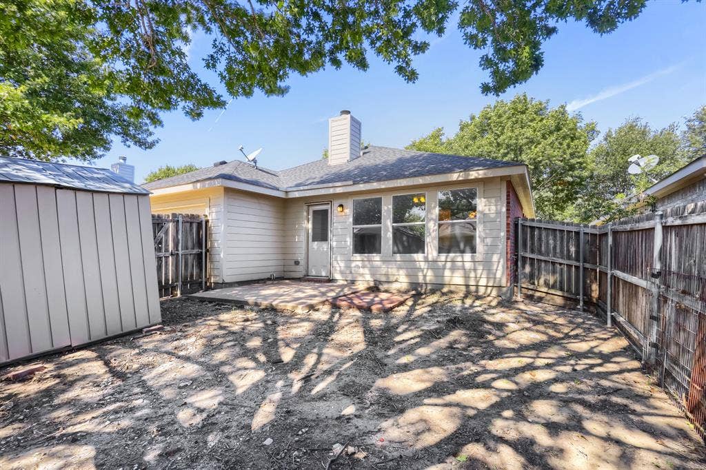 Room featuring wood-finish flooring, vaulted ceilings, multi-pane windows, and a ceiling fan, with double doors opening to a tiled entrance area