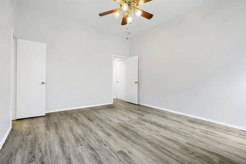 White vanity featuring a rectangular integrated sink, brushed-metal hardware, wood-finish flooring, and a shower-tub combination with white tile surround