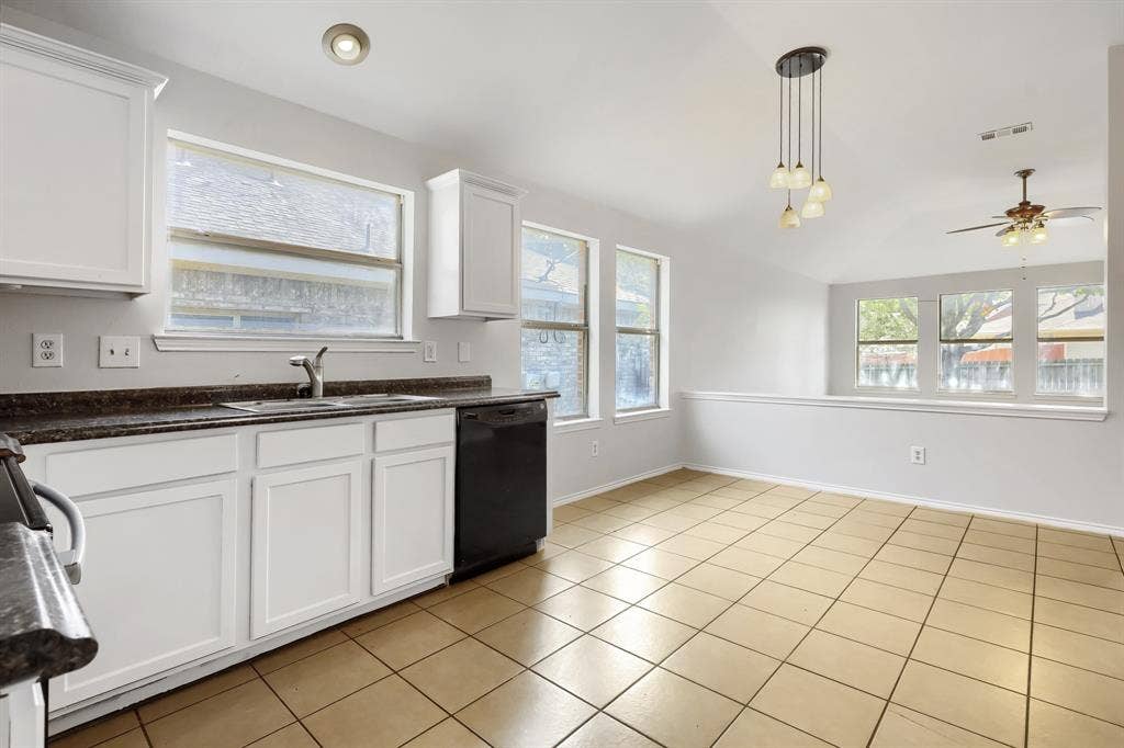 Kitchen featuring white shaker-style cabinetry, stone-finish countertops, stainless steel appliances, ceramic tile flooring, and vaulted ceilings