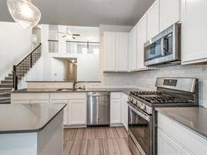 Kitchen featuring white shaker cabinetry, stainless steel appliances, neutral stone-finish countertops, and wood-finish flooring