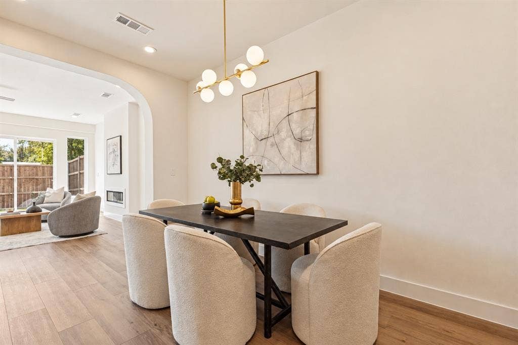 Wood-finish flooring, recessed lighting, and a contemporary linear chandelier illuminate this space