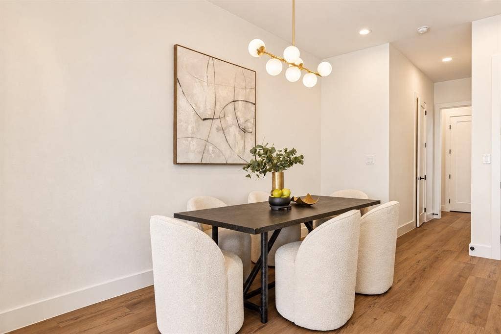 Open-concept dining area featuring wood-finish flooring, recessed lighting, and a modern chandelier