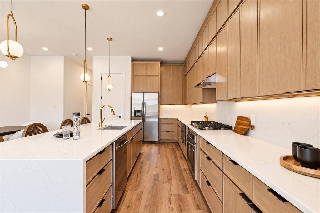 Kitchen with wood-finish cabinetry, stainless steel appliances, white countertops, and wood-finish flooring