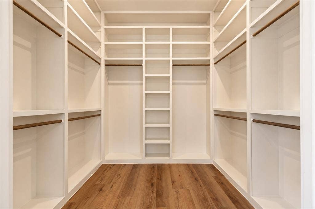 Built-in closet system with multiple shelving units, hanging rods, and wood-finish flooring