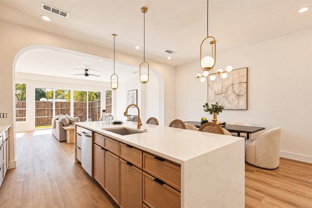 Kitchen island with built-in sink and dishwasher, featuring a light-toned countertop and wood-finish cabinetry