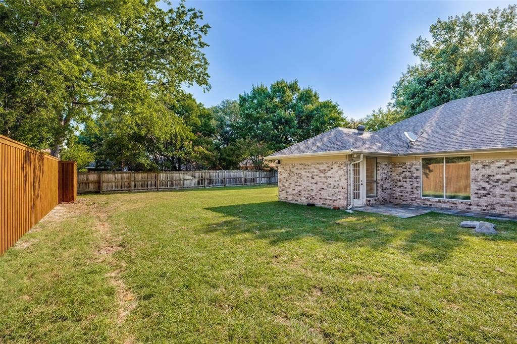 6627 Sawmill Road, Dallas, TX 75252 Expansive backyard featuring a full-perimeter wood privacy fence, brick exterior siding, and mature trees