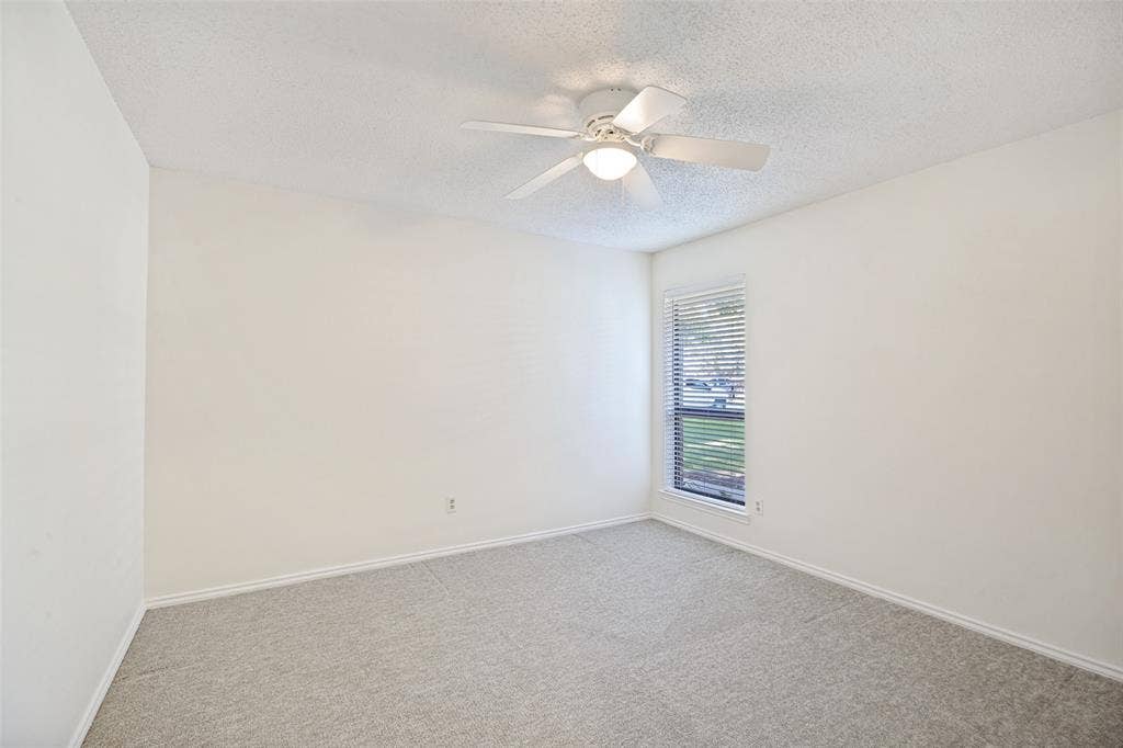 6627 Sawmill Road, Dallas, TX 75252 Neutral-toned wall-to-wall carpeting, ceiling fan with integrated lighting, and window with horizontal blinds