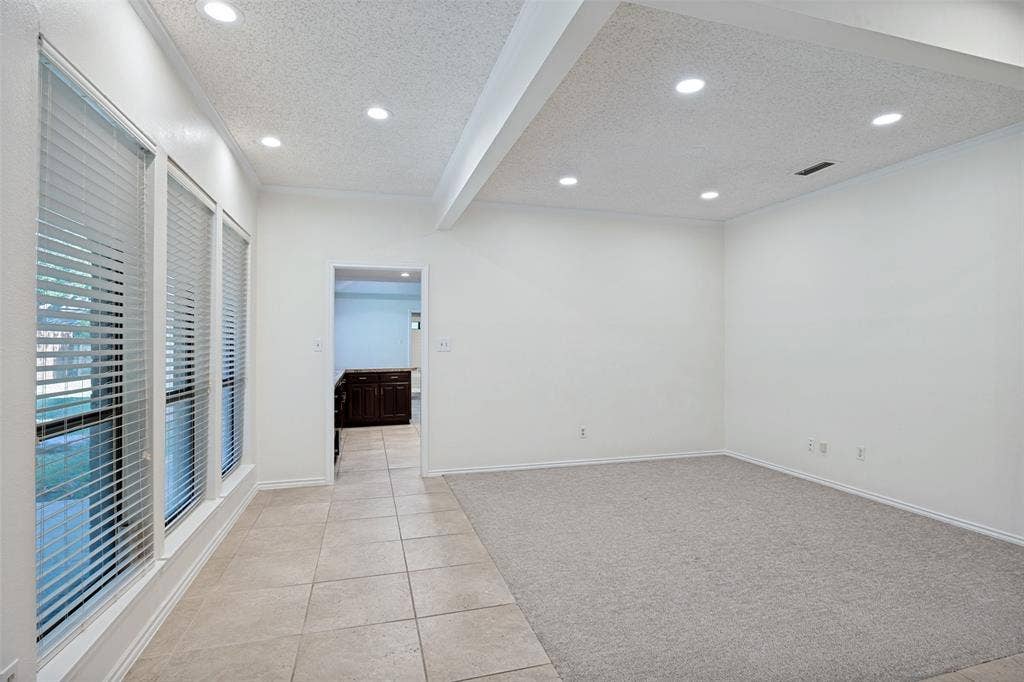 6627 Sawmill Road, Dallas, TX 75252 Room featuring recessed lighting, a tray ceiling, large windows with horizontal blinds, neutral carpeting, and tile flooring
