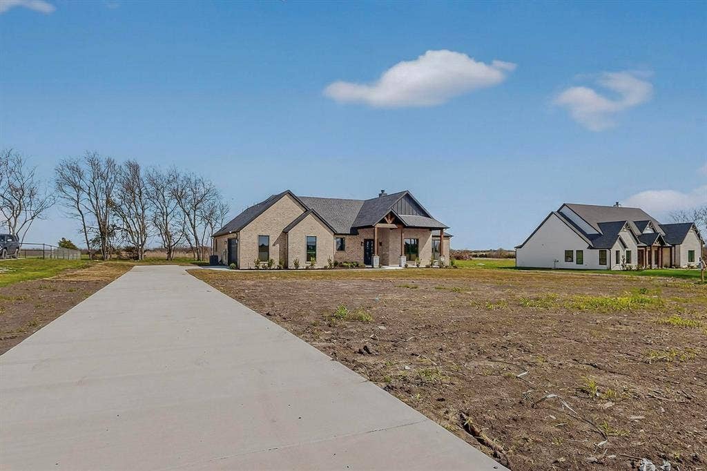 Single-story masonry exterior featuring a gabled roofline, timber-accented covered entryway, and a concrete driveway