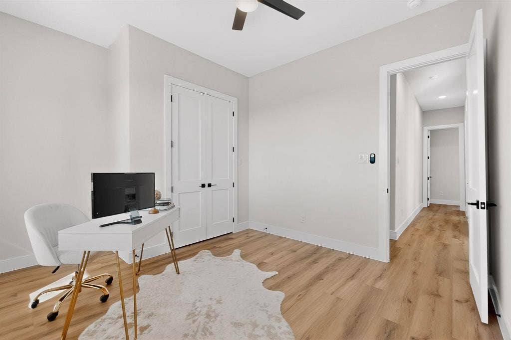 Room featuring wood-finish flooring, white walls, double-door closet with matte black hardware, and a ceiling-mounted light fixture