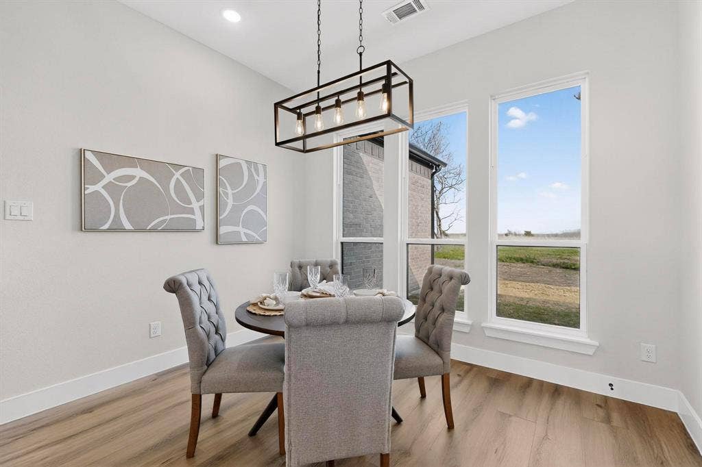 Neutral color palette featuring wood-finish flooring, recessed lighting, and a modern rectangular metal pendant light fixture
