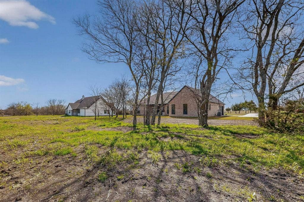 Expansive acreage featuring mature trees, natural landscape, and a multi-structure property with brick and siding exteriors