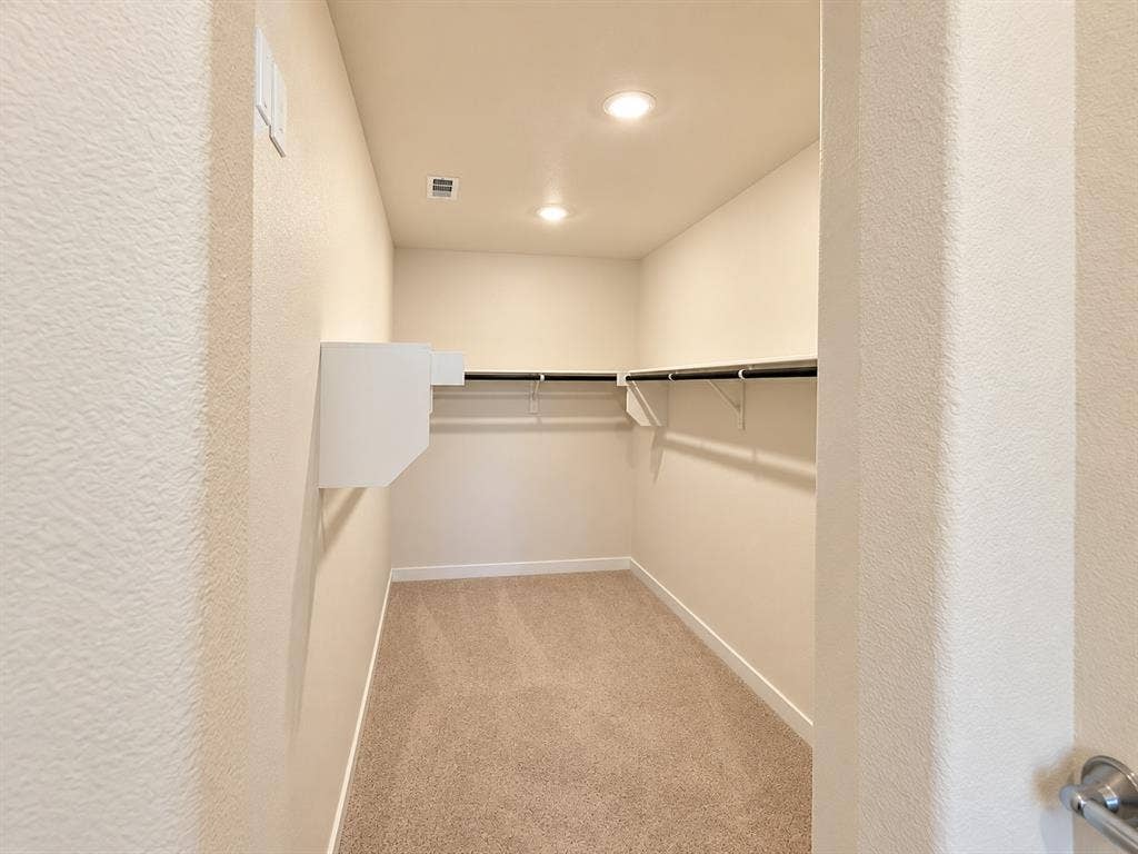 Walk-in closet featuring wall-to-wall carpeting, recessed lighting, and built-in shelving units with integrated garment rods