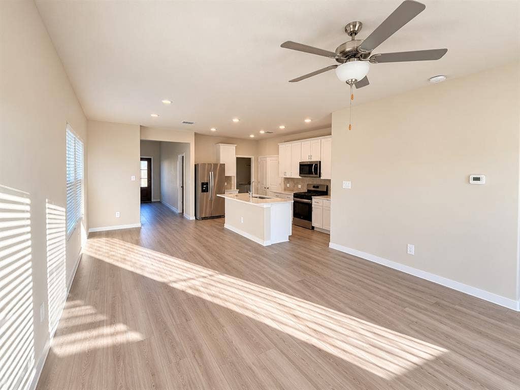 Open-concept space featuring wood-finish flooring, recessed lighting, a center island, shaker-style cabinetry, and stainless-steel appliances
