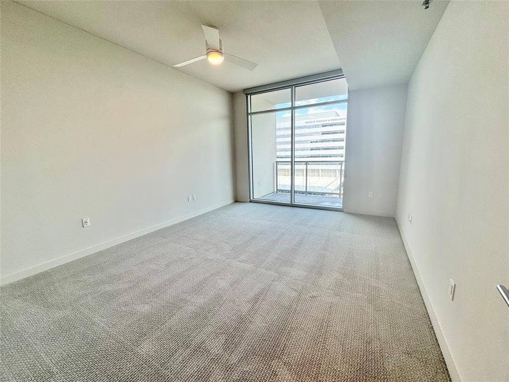 Spare room with light carpet, expansive windows, and ceiling fan