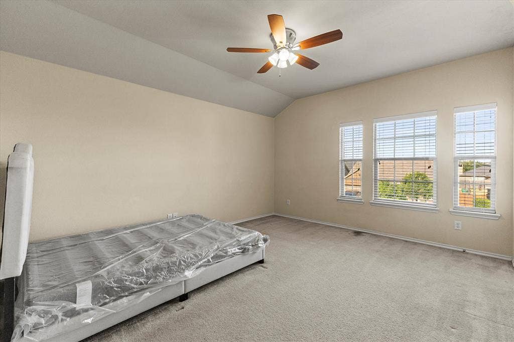 Vaulted ceiling featuring a central five-blade ceiling fan with integrated lighting and three windows with neutral horizontal blinds