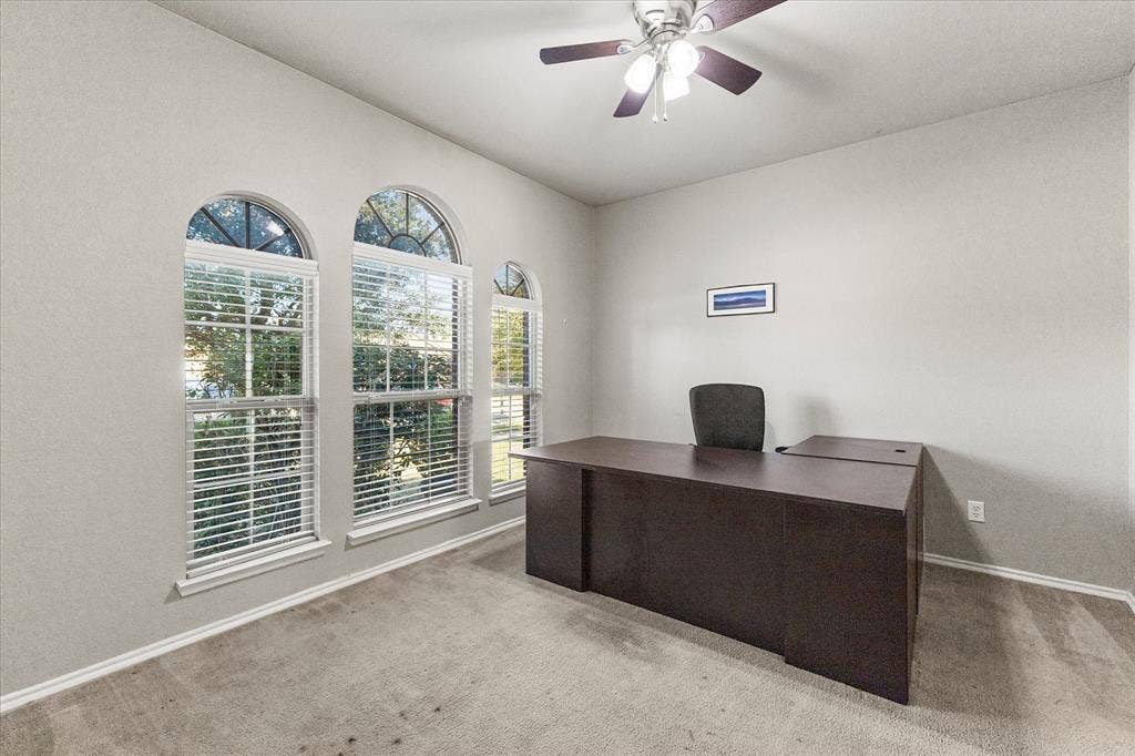 Room featuring arched windows with fanlight detailing, neutral wall tones, carpet flooring, and a ceiling fan with integrated lighting