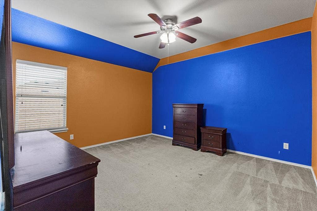 Vaulted ceiling with integrated ceiling fan, neutral carpeting, and horizontal slat window blinds