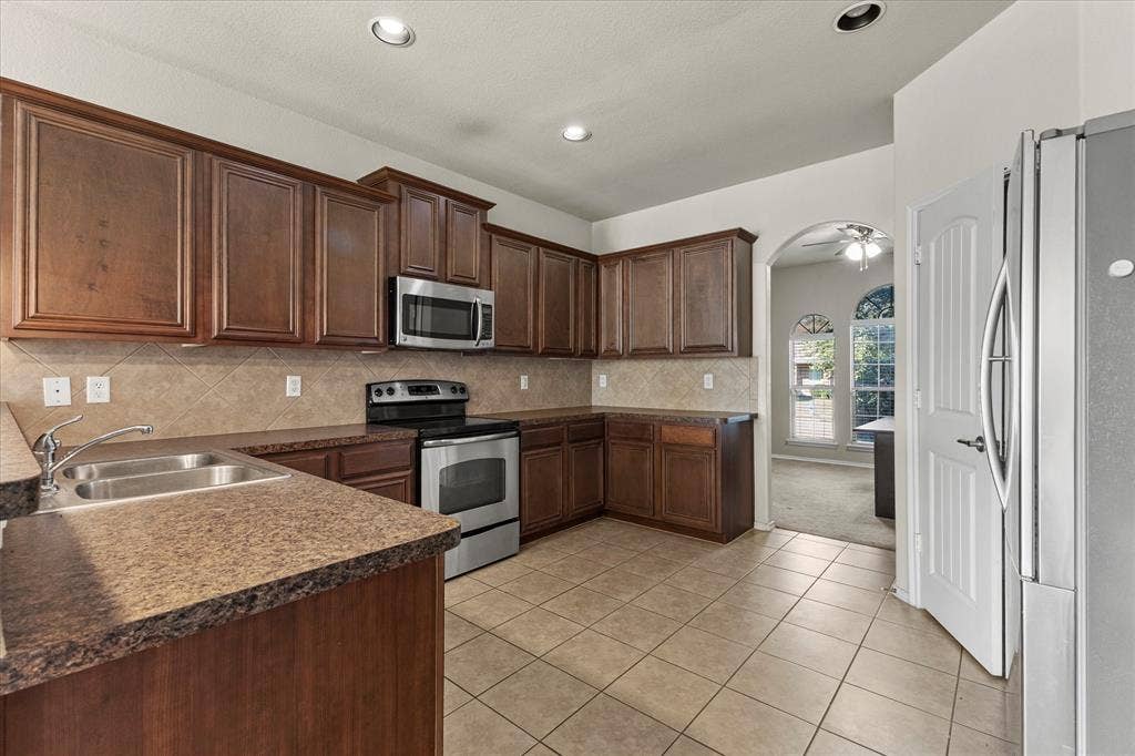 Kitchen featuring dark-finish wood cabinetry, stainless steel appliances, tiled backsplash, ceramic floor tiling, and recessed lighting