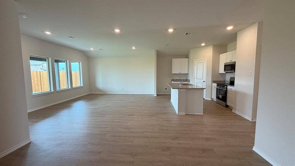 Open-concept living space featuring wood-finish flooring, recessed lighting, and multiple windows