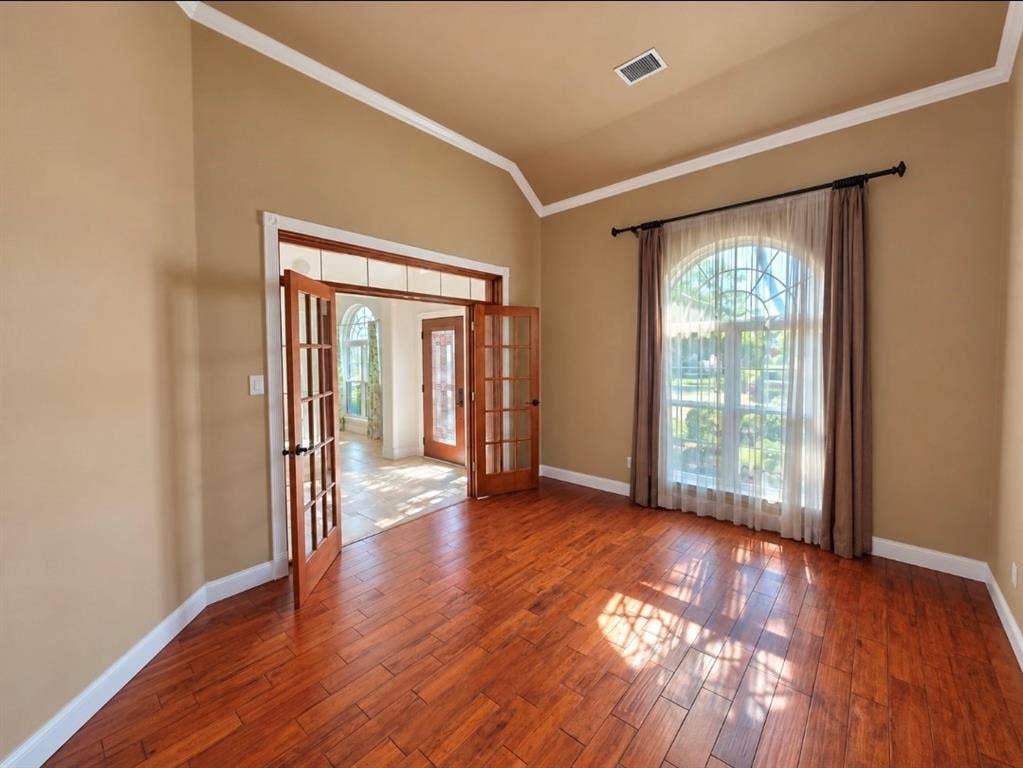 Vaulted ceilings, wood-finish flooring, and arched window with decorative muntins