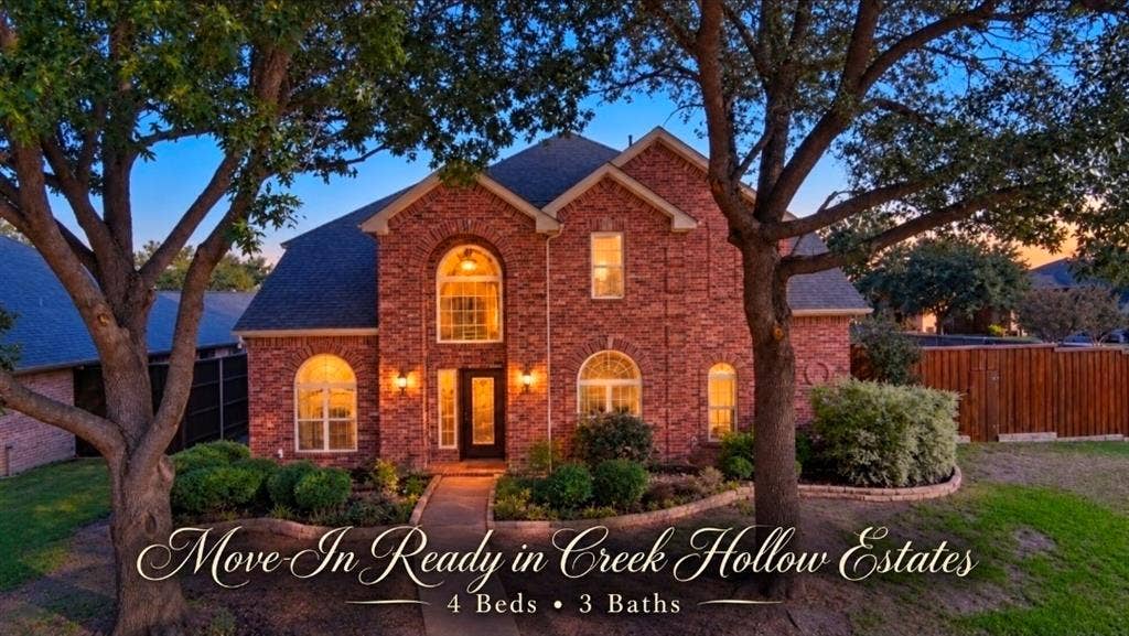 Two-story brick exterior featuring an arched entryway, decorative stone-edged landscaping, and multiple arched windows
