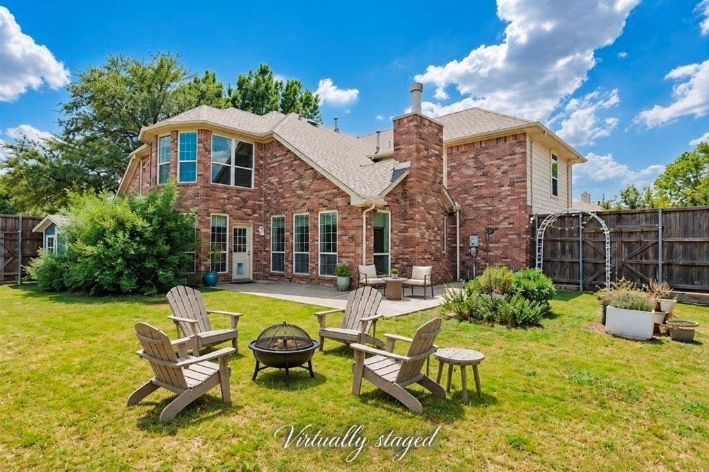 Two-story brick exterior featuring an arched entryway, decorative stone-edged landscaping, and a multi-gabled roofline