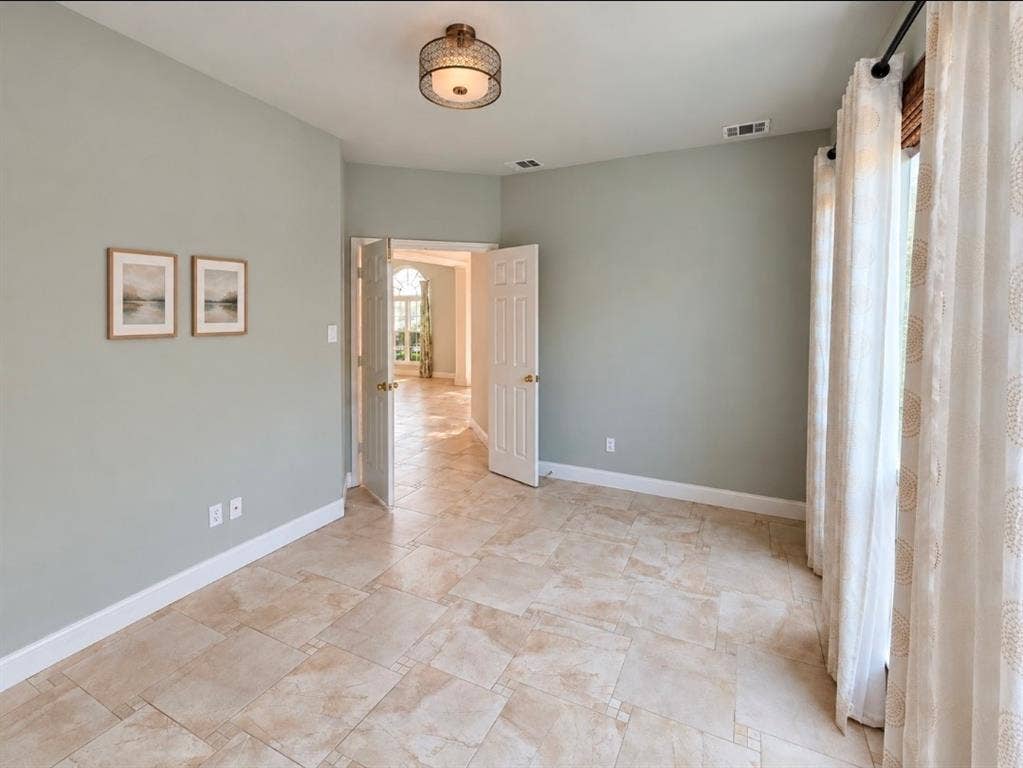 Neutral-toned stone-tile flooring, semi-flush mount drum light fixture, and double-door entry