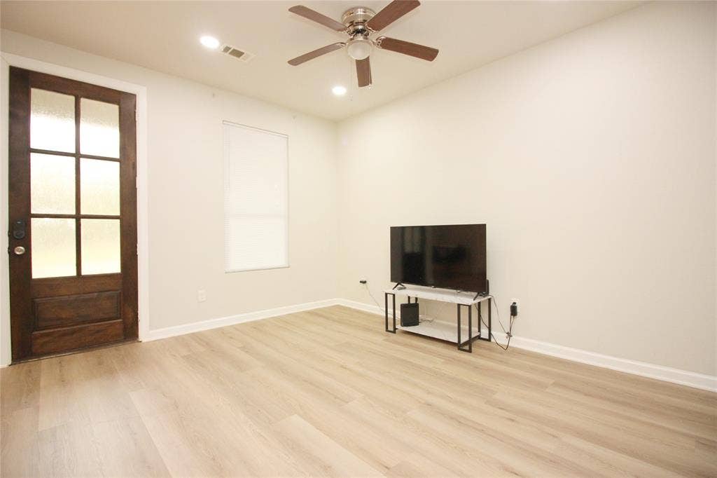 Wood-finish flooring, multi-pane glass door with wood frame, ceiling fan, and recessed lighting