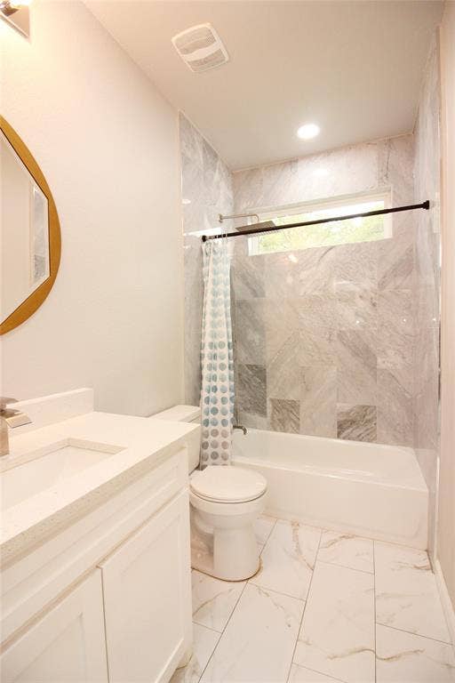 Bathroom featuring large-format stone-look tile flooring, white cabinetry with a light-toned solid surface countertop, and a tub-shower combination enclosed by floor-to-ceiling decorative stone-look wall tile